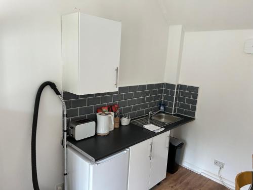 uma pequena cozinha com uma parede de azulejos pretos em The Diary em Takeley