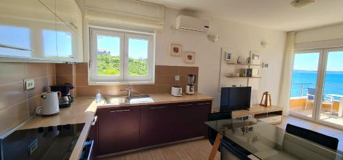 a kitchen with a sink and two windows with the ocean at Apartments Nicolas - Beach & Sea 10m away - Amazing sea view! in Rtina