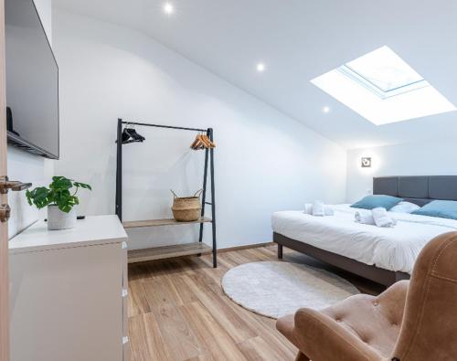 a white bedroom with a bed and a chair at Trois pièces cozy n14 in Nice