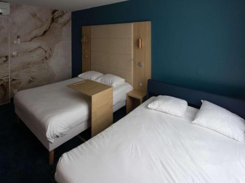 una habitación con 2 camas y una mesa entre ellas en ibis Styles Chinon, en Chinon