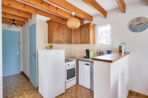 une cuisine avec des appareils électroménagers blancs et des armoires en bois dans l'établissement Plobannalec-Lesconil centre - Maison avec grand jardin, à Plobannalec-Lesconil
