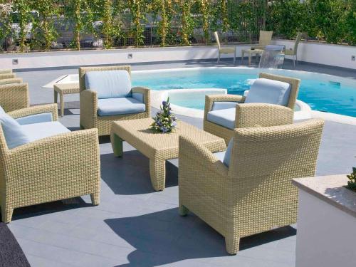 a group of chairs and tables next to a pool at Mercure Rimini Lungomare in Rimini