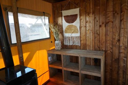 a room with a wooden wall with a bench and a window at Luxe en sfeervolle safaritent met eigen badkamer voor 6 personen Doc in Behelp