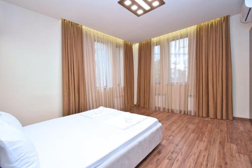a bedroom with a bed and two large windows at Luxury White House In Yerevan in Yerevan