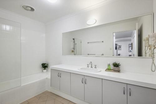 a white bathroom with a sink and a mirror at Northbridge Hideaway 2BDR 1BTH in Perth