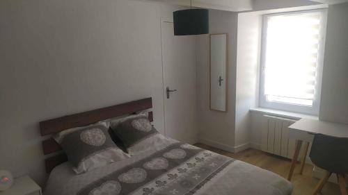 une chambre avec un lit avec des oreillers et une fenêtre dans l'établissement Cœur de Ville Yffiniac, à Yffiniac