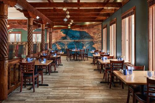 タオスにあるHilton Tapestry Collection, Hotel Don Fernando De Taosの木製のテーブルと椅子、壁画のあるレストラン