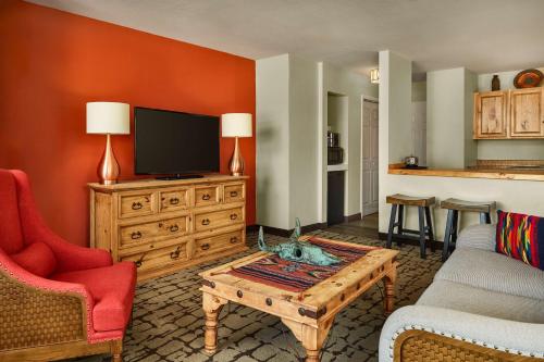 ein Wohnzimmer mit einem TV, einem Sofa und einem Couchtisch in der Unterkunft Hilton Tapestry Collection, Hotel Don Fernando De Taos in Taos