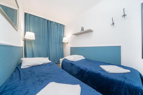 dwa łóżka w małym pokoju z niebieskimi prześcieradłami w obiekcie MGR Pokoje w samym Centrum Warszawy by Metro Rondo ONZ - SUPER Bed Year23 w Warszawie