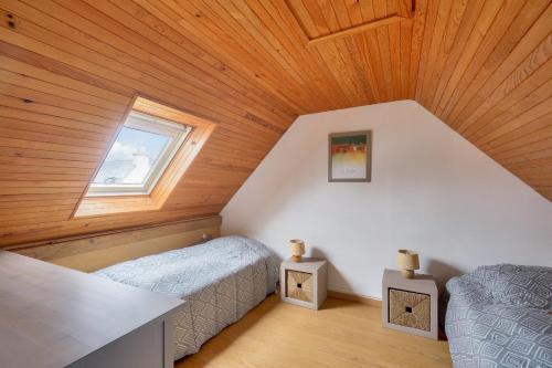 een slaapkamer op zolder met 2 bedden en een raam bij Plage et decouverte de la Bretagne in Plobannalec-Lesconil