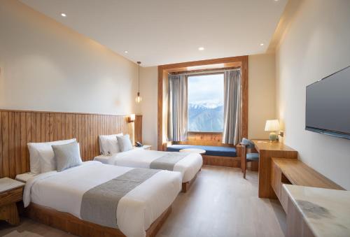 a hotel room with two beds and a flat screen tv at The Highland Ladakh in Leh