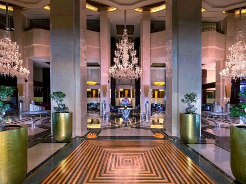 a hotel lobby with a chandelier and a large hallway at La Cigale Hotel Managed by Accor in Doha