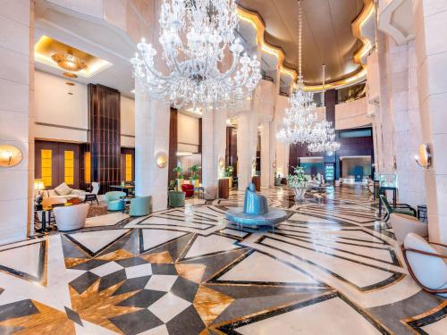 a lobby of a hotel with chandeliers and a large lobby at La Cigale Hotel Managed by Accor in Doha