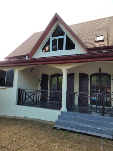 a house with a porch and a roof at Villa charmante à Saint-Benoît avec piscine privée in Saint-Benoît
