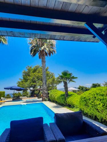 a swimming pool with two blue chairs and palm trees at Villa Palma Posidi with Private pool in Kalandra