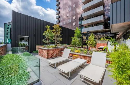 a patio with two white chairs and some plants at Luxury Docklands Loft 2B1B River view & Free parking in Melbourne