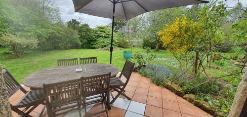 a table and chairs with an umbrella on a patio at Domaine La Bonne Etoile in Le Faouët