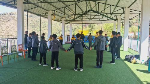 a group of young people holding hands in a building at The Himalaya Retreat Resort, Experience Nature in the Lap of Himalayas in Mussoorie
