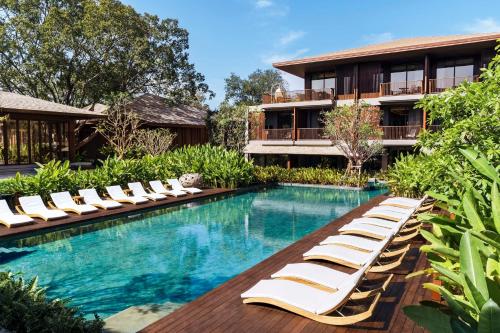 - une piscine avec des chaises longues à côté d'un bâtiment dans l'établissement Andaz Pattaya Jomtien Beach, a Concept by Hyatt, à Na Jomtien