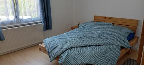 a bedroom with a bed with a blue comforter and a window at Ferienhaus Kallenfels in Kirn