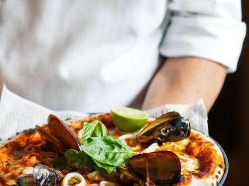 a person holding a pizza with mussels and a lime at Swissotel Uludag Bursa in Bursa