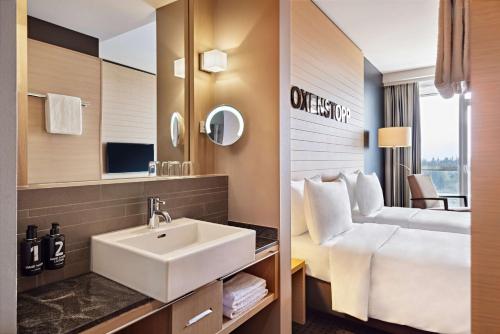 ein Badezimmer mit einem Waschbecken und einem Bett in der Unterkunft Lindner Hotel Nurburgring Congress, part of JdV by Hyatt in Nürburg