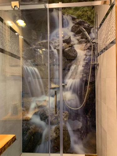 a waterfall mural is shown in a shower stall at Willa Kobiela in Witów