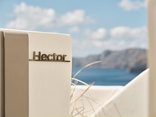een bord met Horo op een wit hek met uitzicht op de oceaan bij Andronis Boutique Hotel in Oia