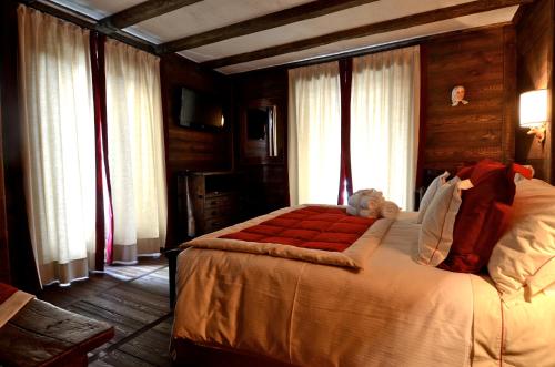 una camera con un grande letto in una stanza con finestre di Hotel Chalet Il Capricorno a Sauze d'Oulx