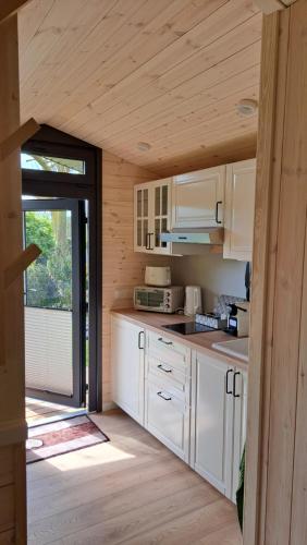 a kitchen with white cabinets and a large window at Sauerland Tinyworld in Diemelsee