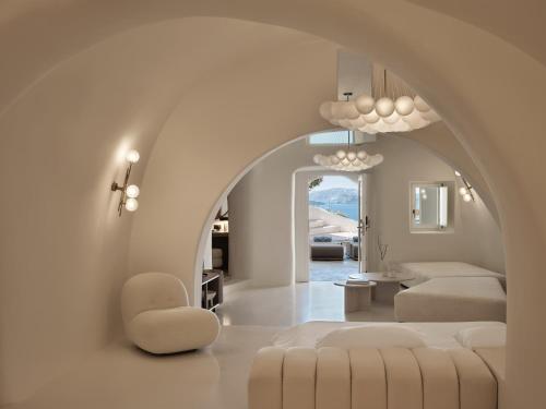 a living room with an archway and a couch and chair at Andronis Boutique Hotel in Oia