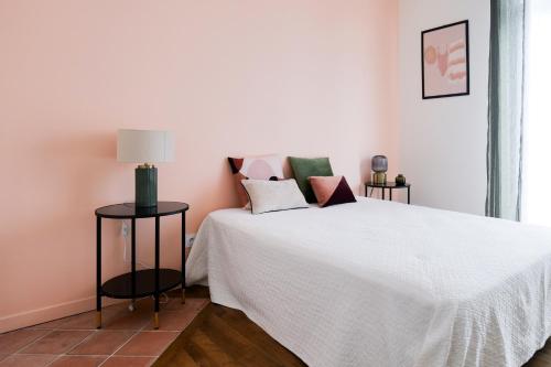a bedroom with a white bed with pink walls at Jolie maison rénovée dans le centre-ville avec garage privatif Les Sables 4 personnes in Les Sables-dʼOlonne