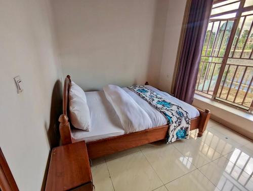 uma pequena cama num quarto com uma janela em Inshuti Home Stay 