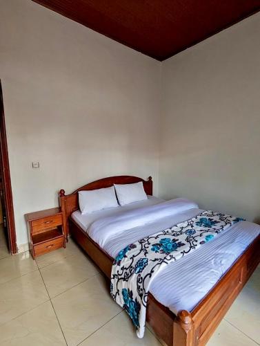 a bedroom with a bed and a night stand at Inshuti Home Stay in Gasanze