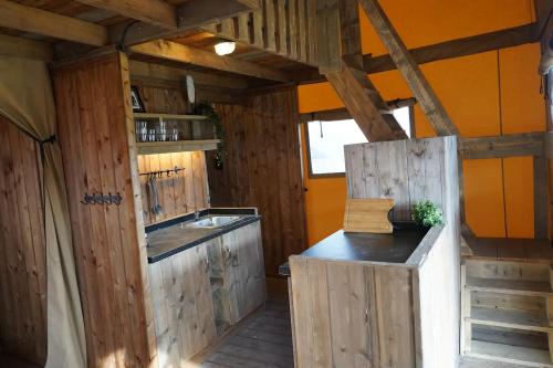 a kitchen with wooden cabinets and a counter in a room at Glamping met bar en privé sanitair voor 5 Personen Sneezy in Behelp