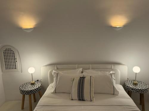 a white bedroom with a bed with two night stands at Ater Albus Collection by K&K in Imerovigli