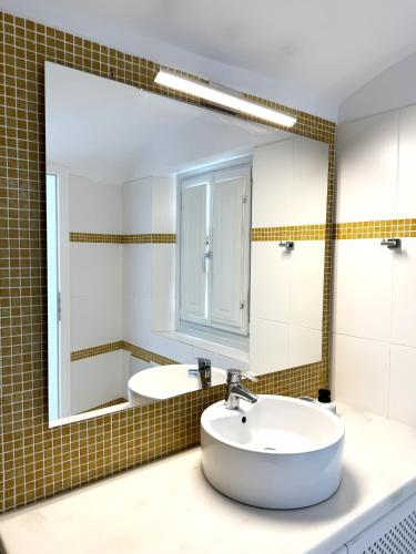 a bathroom with a sink and a large mirror at Ater Albus Collection by K&K in Imerovigli