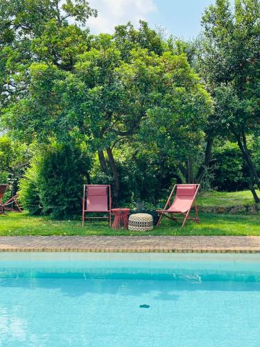 two chairs and a table next to a swimming pool at Relais Villa dei Gelsi & Spa in Verona