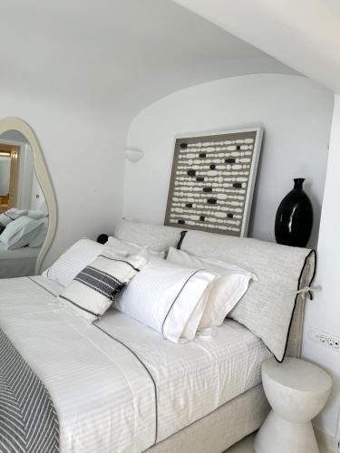 a white bedroom with a bed with a mirror at Ater Albus Collection by K&K in Imerovigli