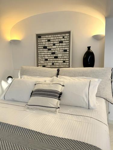 a bedroom with a white bed with white pillows at Ater Albus Collection by K&K in Imerovigli