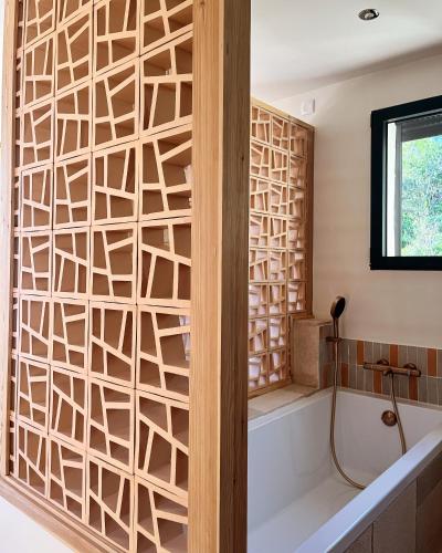 La salle de bains est pourvue d'une cloison en bois et d'une baignoire. dans l'établissement La Maison de la Genette - 5 étoiles, à Cavalaire-sur-Mer