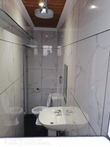 a white bathroom with a sink and a toilet at Freedommedia guesthouse in Gqeberha