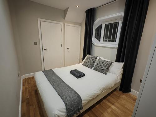 a bedroom with a white bed with a black pillow at New! Lovely 2 Bed Serviced Apartment with free parking in London