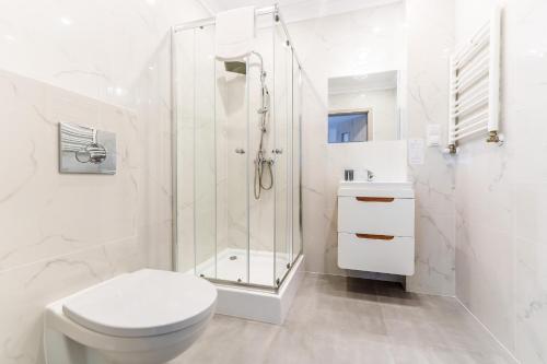 a white bathroom with a shower and a toilet at Nadmorski Apartament I by Holiday&Sun in Grzybowo