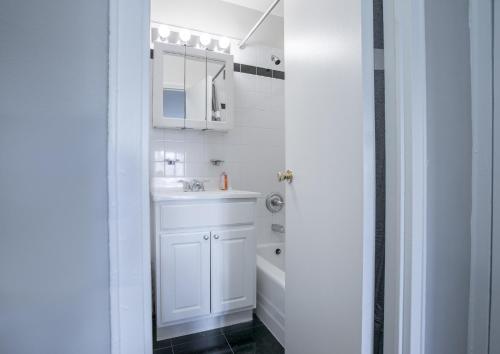 a white bathroom with a sink and a tub at Spectacular 2 Beds/2 Baths Apartment in New York