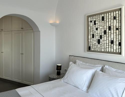 a bedroom with a white bed and a cabinet at Ater Albus Collection by K&K in Imerovigli