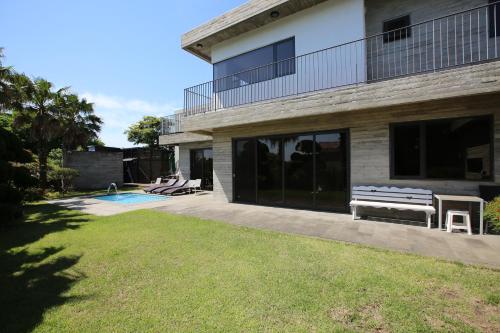 a house with a bench next to a swimming pool at Jeju Private unit for family or group in Jeju