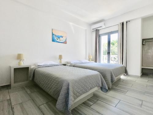 two beds in a white room with a window at Anny Studios & Rooms Perissa Beach in Perissa