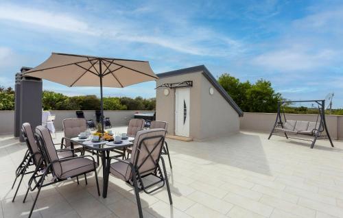 Una mesa con sillas y una sombrilla en un patio. en Pet Friendly Home In Pula With Wifi, en Pula