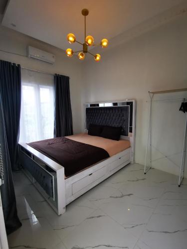 - une chambre avec un grand lit et un lustre dans l'établissement LOBLUS (Low Budget Luxury Stay), à Padang